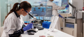 Biotechnology scientist looking through microscope analyzing genetical material. Medicine, biotechnology researcher in advanced pharma lab, examining virus evolution.
